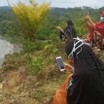 Mahasiswa di pedalaman Aceh Barat saat duduk di atas bukit pinggir sungai mencari akses jaringan internet untuk mengikuti proses belajar daring. Foto: Dok. acehkini