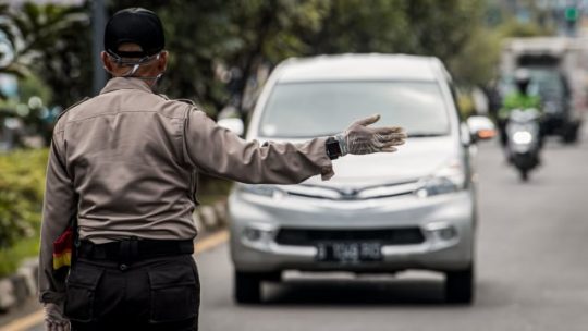 Polisi mengarahkan kendaraan roda empat untuk menjalani pemeriksaan saat penerapan Pembatasan Sosial Berskala Besar (PSBB).. Foto: Antara/Agung Rajasa