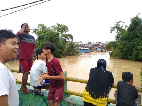 Sejumlah warga menyaksikan banjir besar yang terjadi di Sungai Deli dari atas jembatan di Jalan Juanda Baru, Medan, pada Jumat (4/12). Foto : Sumut News